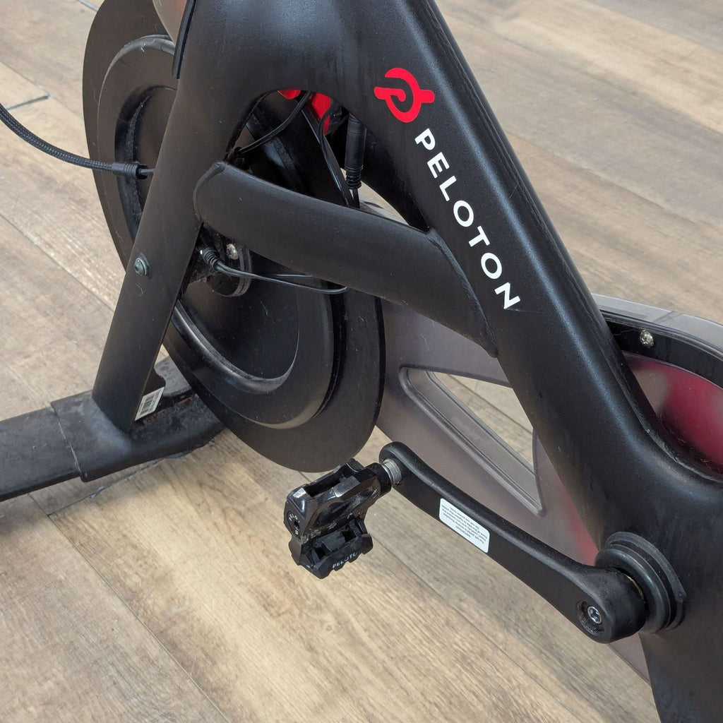 3. Close-up of the Peloton Exercise Bike's pedal and frame, highlighting the sturdy build and brand logo.