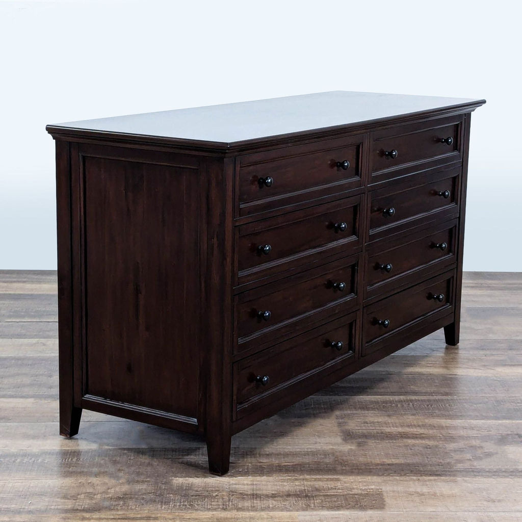 3. Side perspective of Pottery Barn dresser featuring dark wood, recessed panels, and 8 drawers.