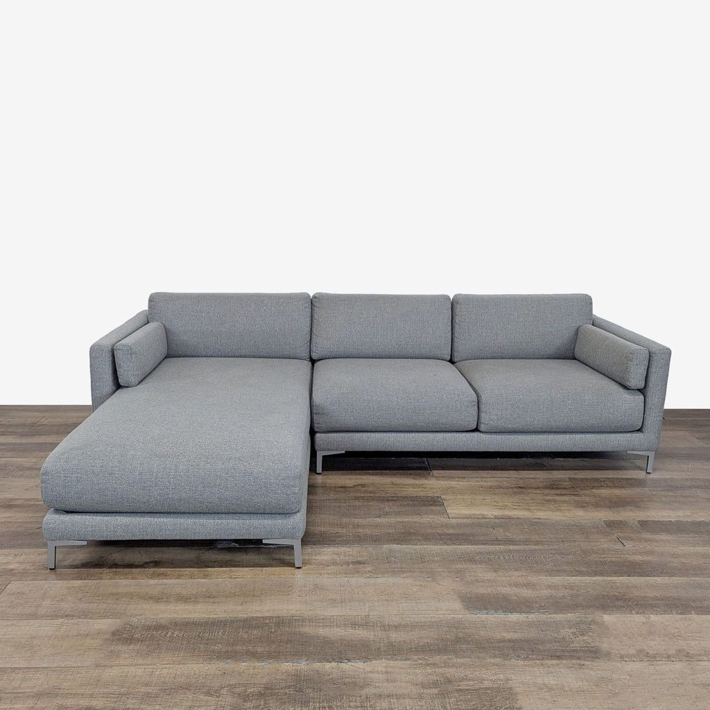 1. CB2 sectional sofa with chaise, track arms, and metal legs, shown in a front view on wood flooring.  