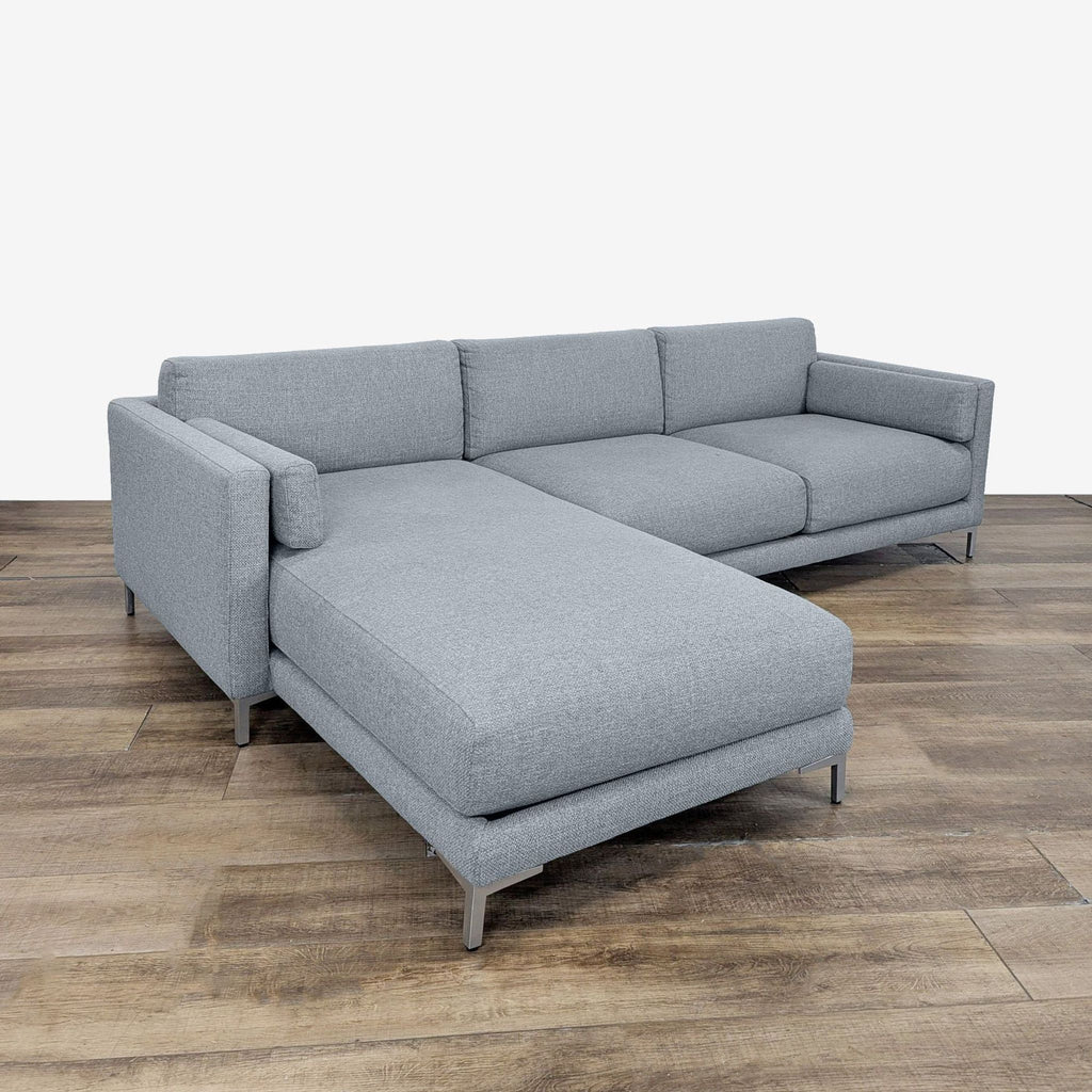 2. Modern gray CB2 sectional with chaise lounge, track arms, and metal legs, angled on wooden floor.  