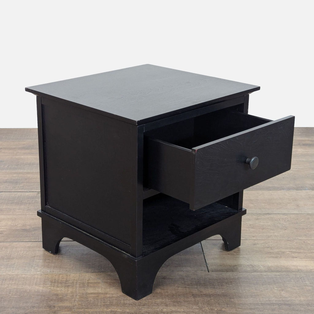 2. Angled view of a black console table by Pottery Barn, featuring an open drawer and lower open shelf.