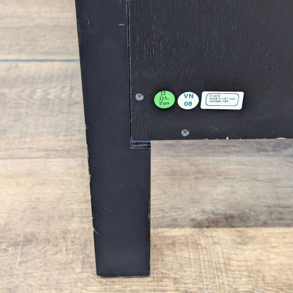 Close-up of back leg of Pottery Barn end table with quality assurance and manufacturing labels visible.