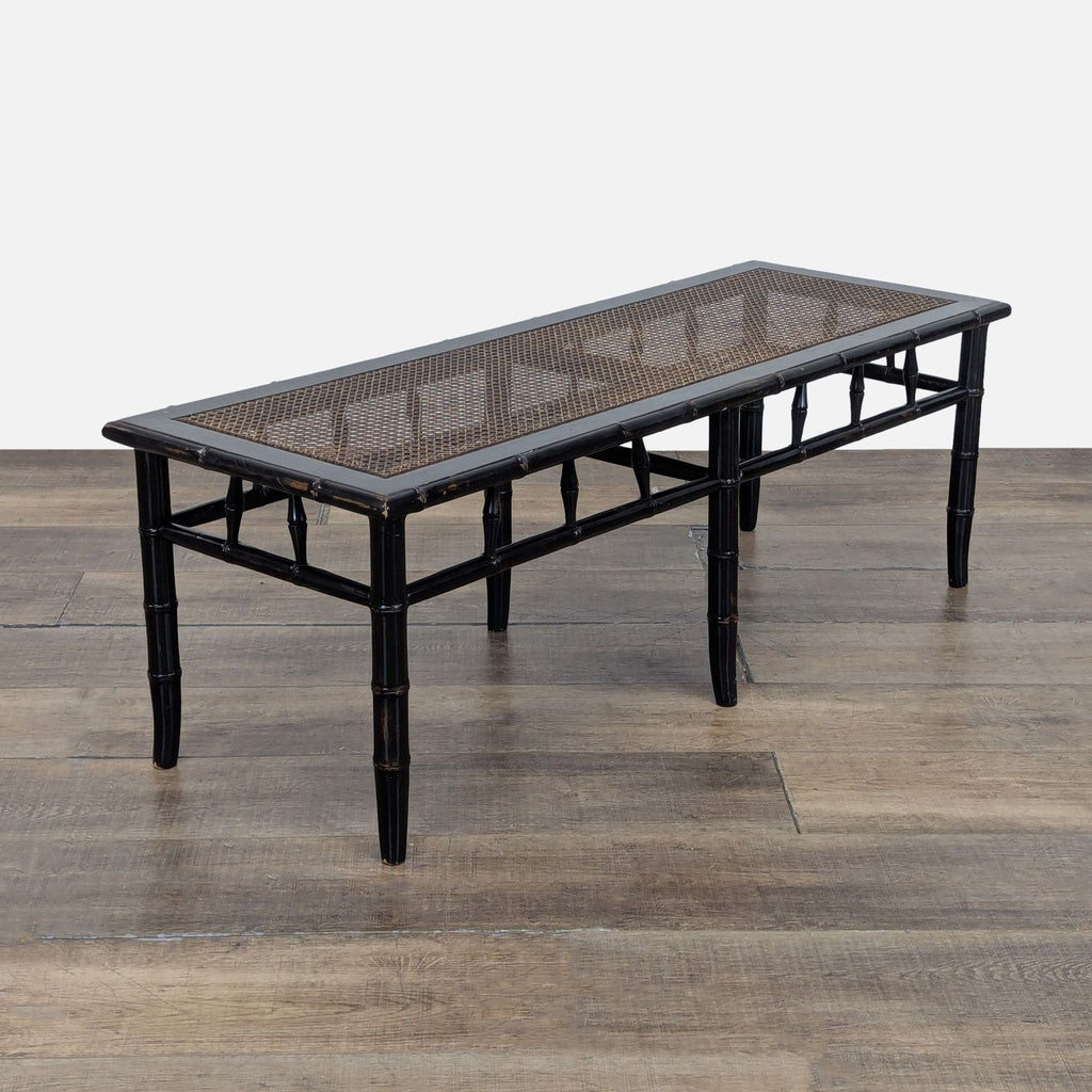 2. Angled view of a Reperch bench featuring a dark bamboo-inspired frame and cane woven top, on a wood floor.