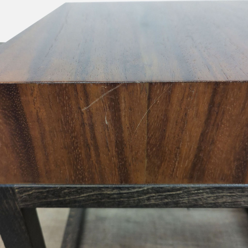 Close-up of a Crate & Barrel side table showing wood grain detail and minor surface scratches on the edge.  
