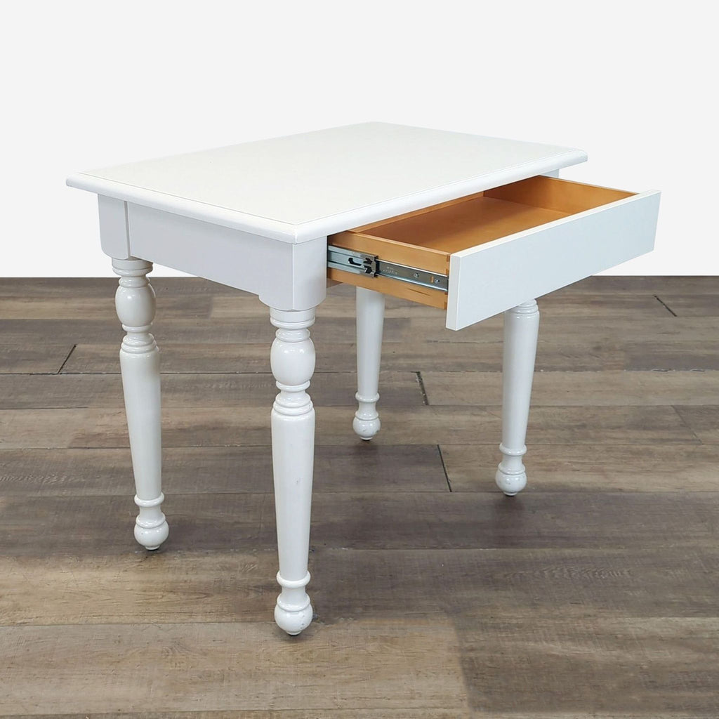 Reperch end table in white with classic turned legs, featuring an open drawer, for living room use.