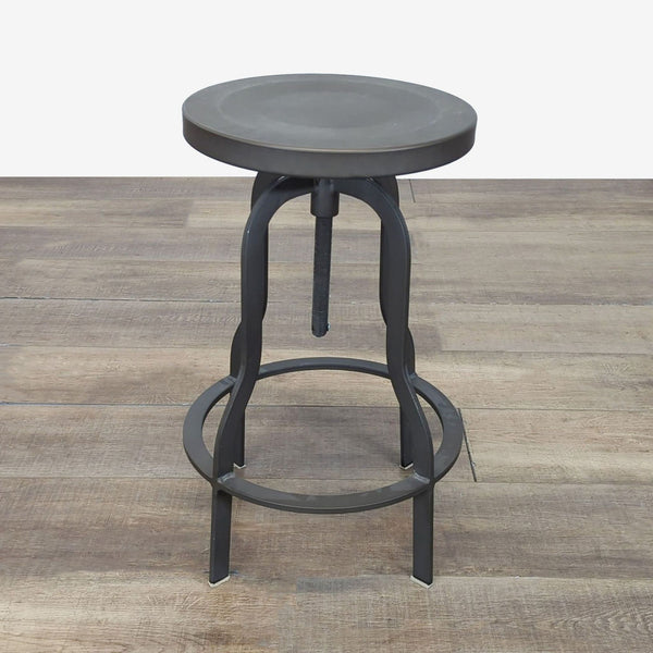 1. Industrial-style metal stool with circular seat and footrest, photographed on a wooden floor, by Structube.
