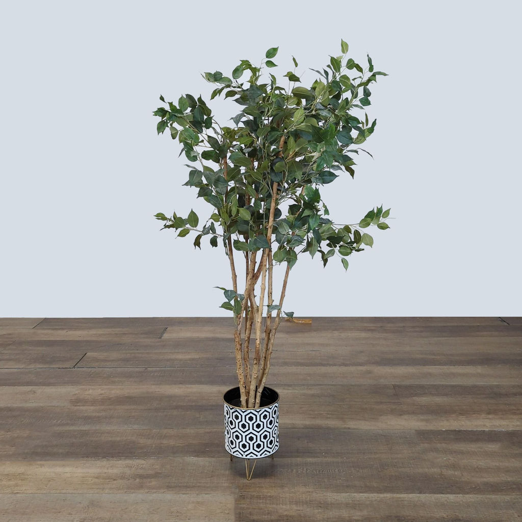 1. Artificial leafy plant in Reperch black and white geometric pot with tripod stand on a wooden floor.