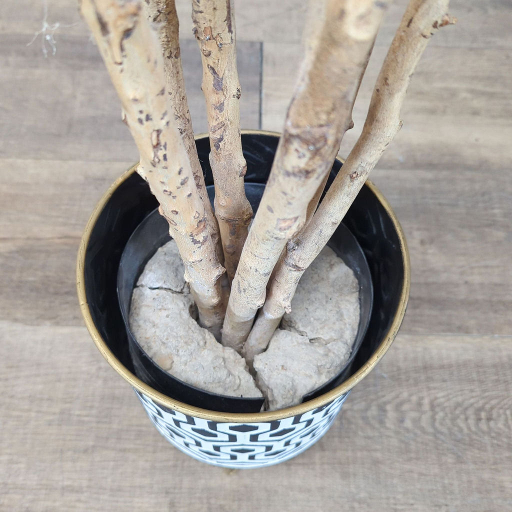 2. Close-up of artificial tree trunks set in a Reperch patterned pot, showing textured faux soil base.
