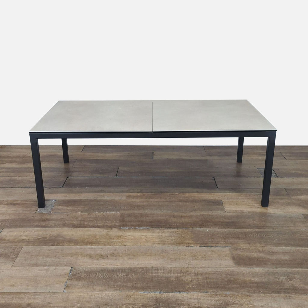 1. Room and Board dining table with ceramic taupe top and 2-inch thick natural steel legs, shown on wood floor.  