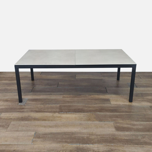 1. Room and Board dining table with ceramic taupe top and 2-inch thick natural steel legs, shown on wood floor.  