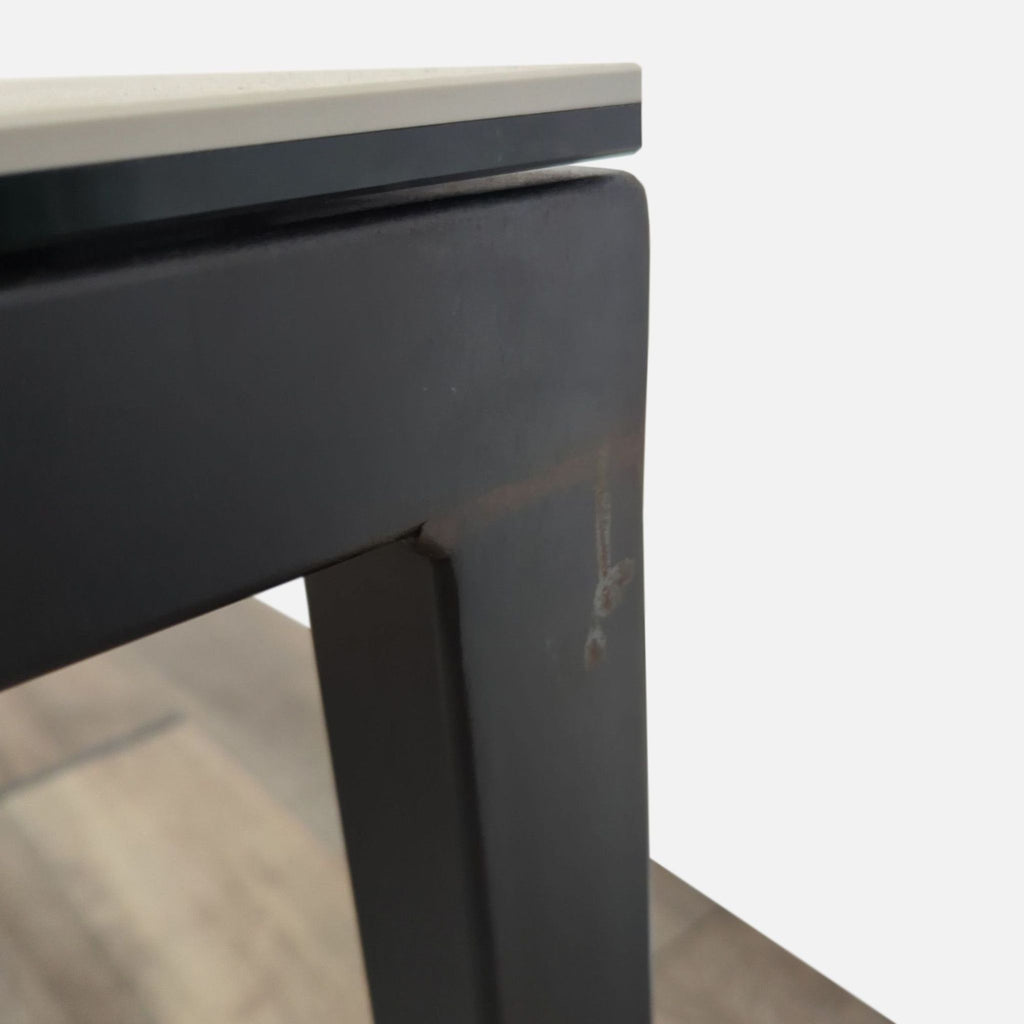 2. Close-up of Room and Board dining table leg in natural steel finish and edge of ceramic taupe tabletop.  