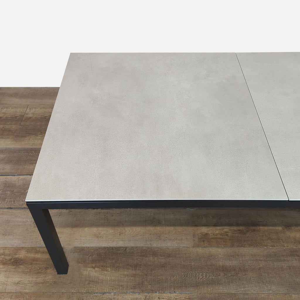 3. Partial overhead of Room and Board dining table, highlighting ceramic taupe surface and steel frame construction.