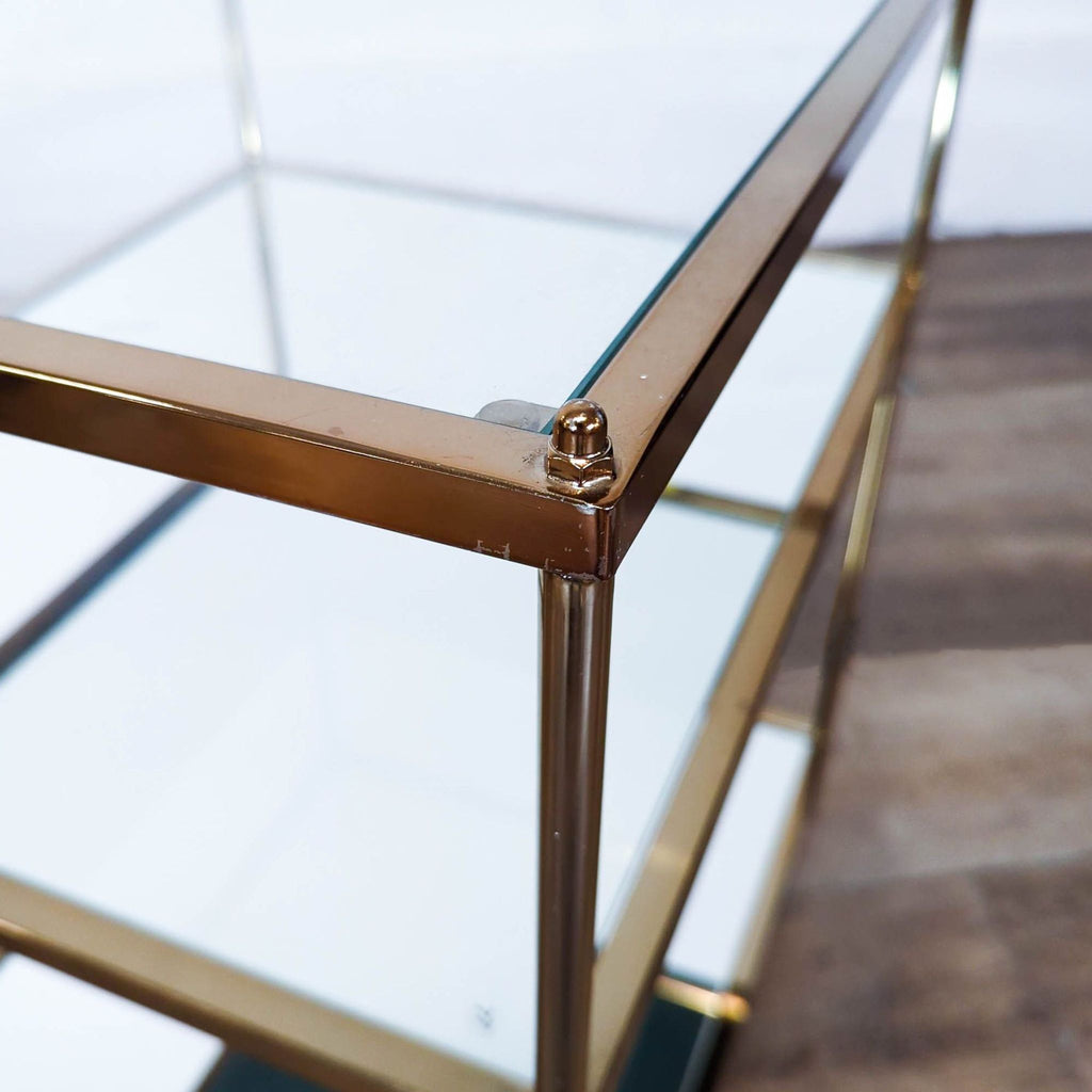 3. Close-up of the Reperch side table showing the gold metal frame and glass and mirrored shelves.