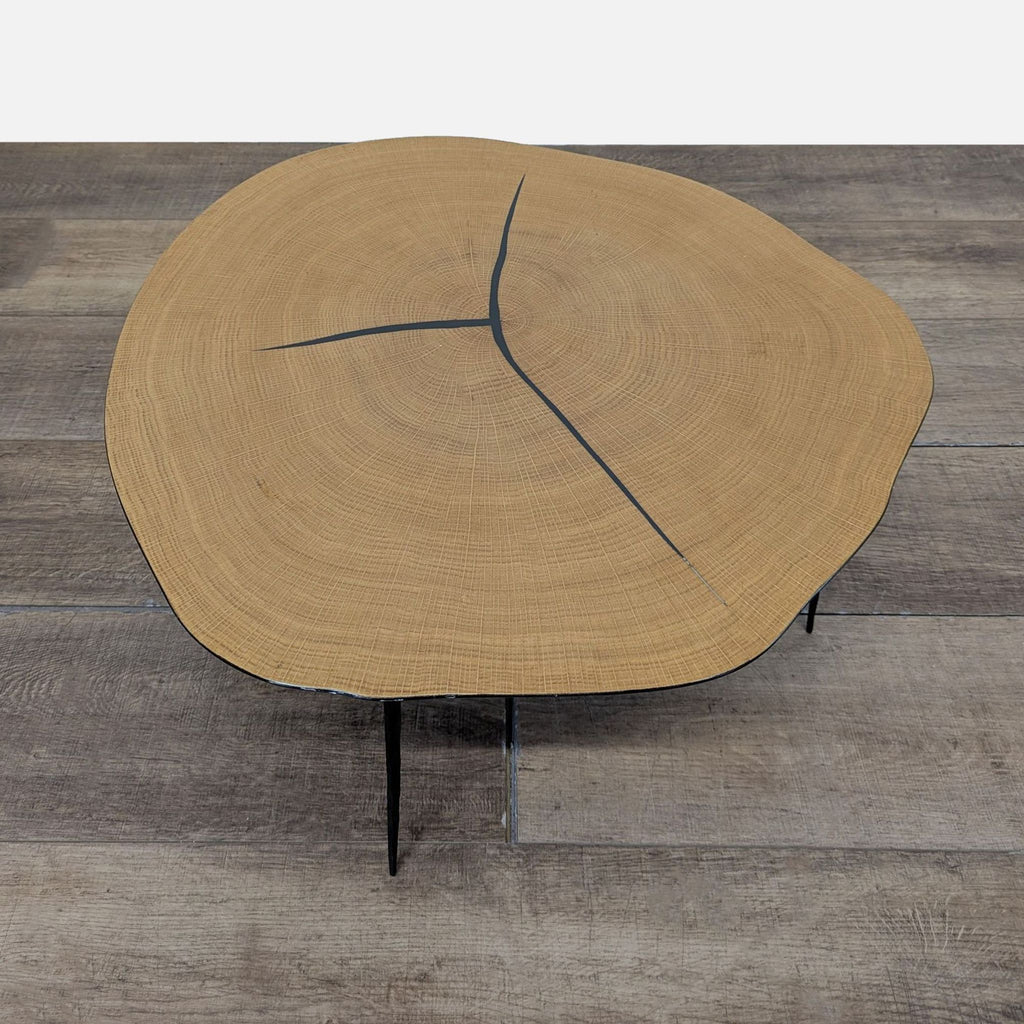 3. Unique Industry West coffee table, wood top with growth rings and black inlays, set on three slender legs.