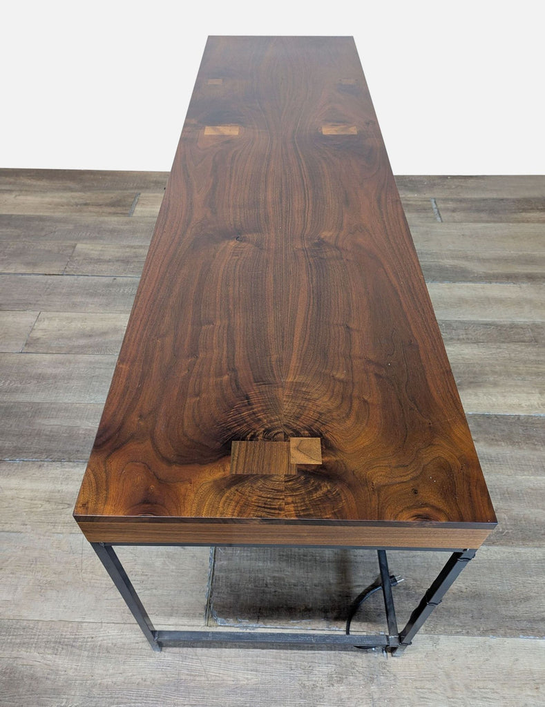 2. Top view of a Reperch desk with a rich wood surface, visible grain, and a metal base with cord management.  