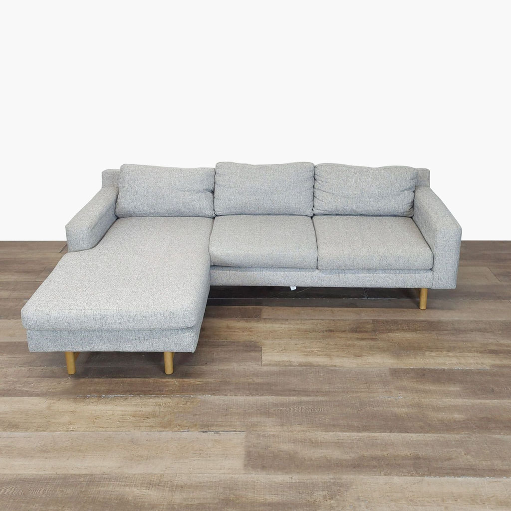 1. Light gray Reperch sectional with chaise lounge, wide seat, padded back, and wooden legs on wood flooring.
