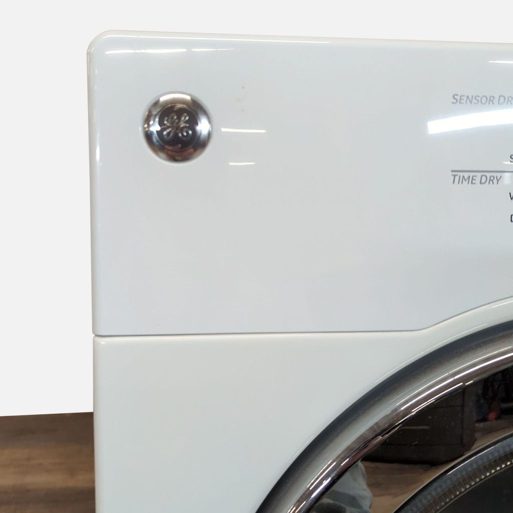 3. Close-up of the GE washer/dryer brand logo and part of the control panel on a white appliance exterior.