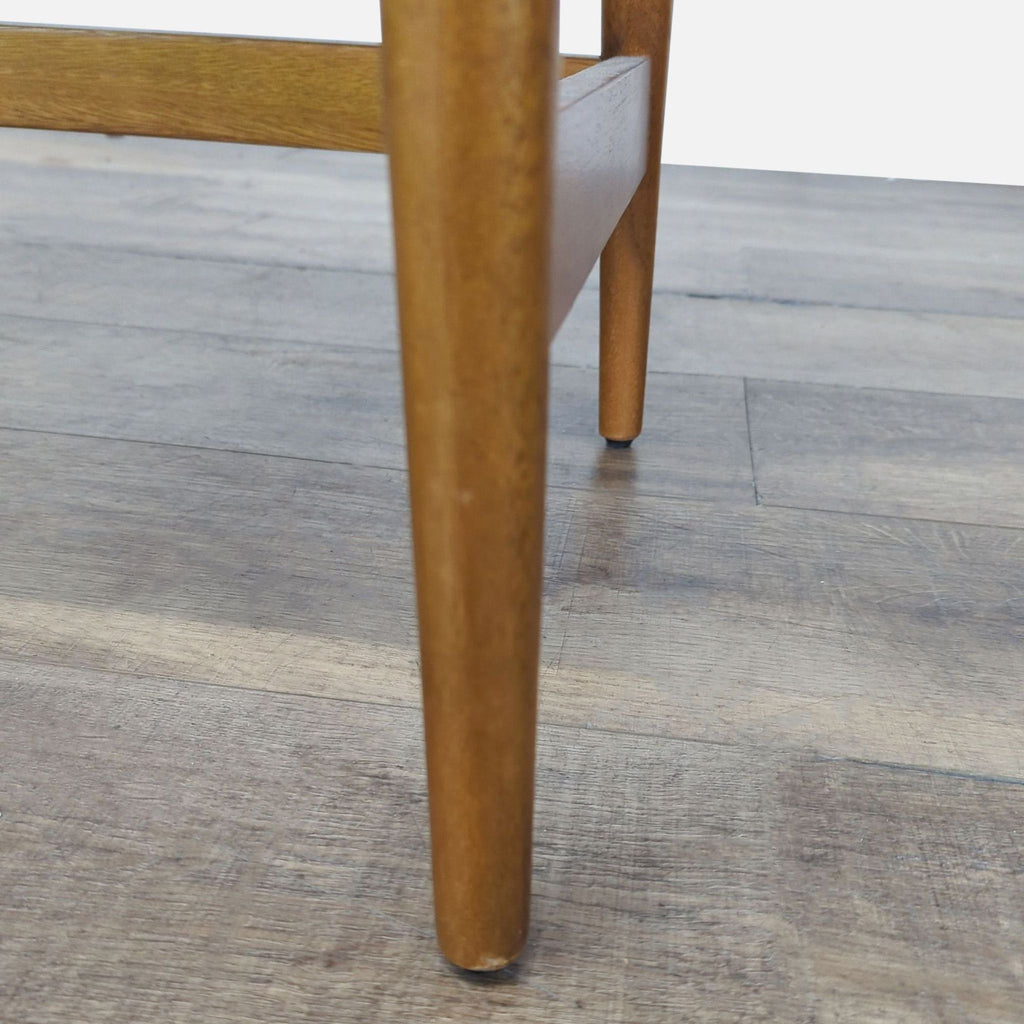 Close-up of a tapered wooden leg from a West Elm desk, highlighting sturdy construction and finish.