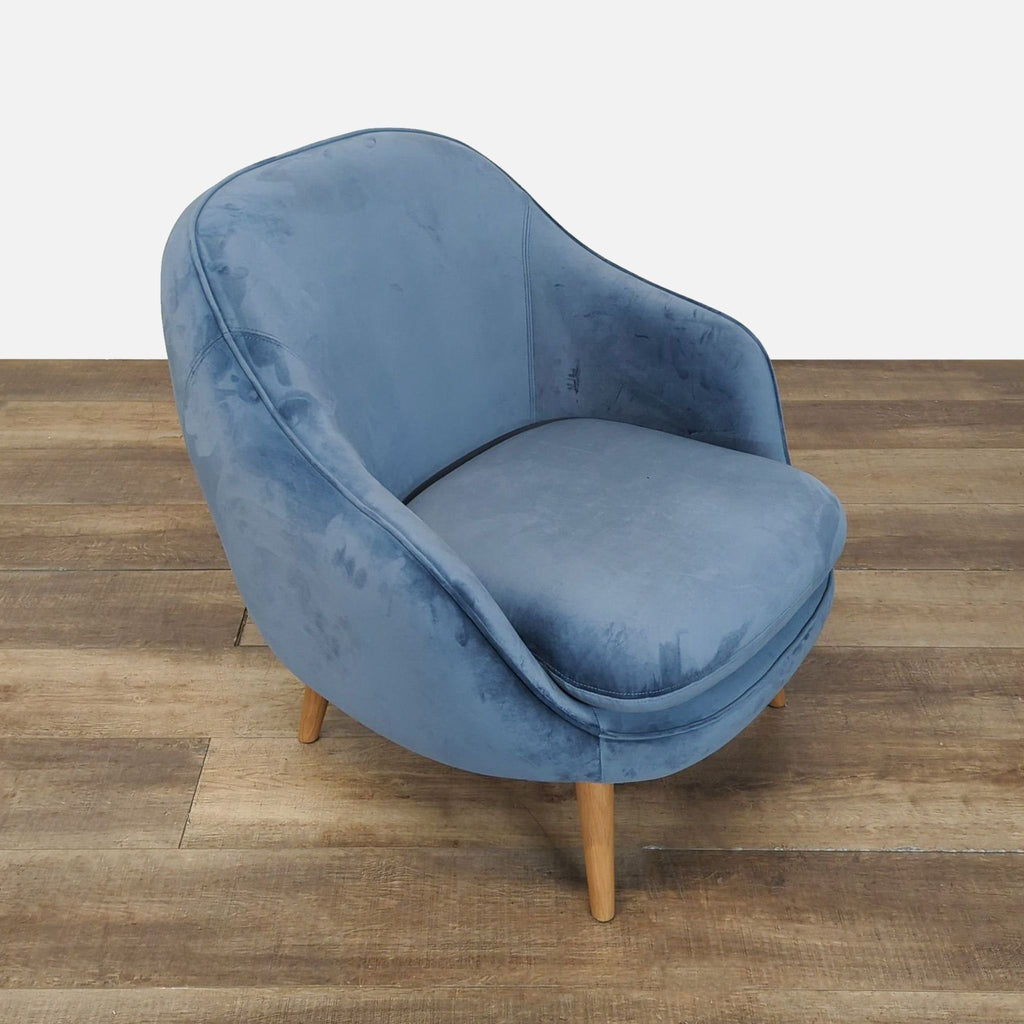 Angled side view of a dust blue velvet lounge chair by Industry West, featuring natural wood legs.  