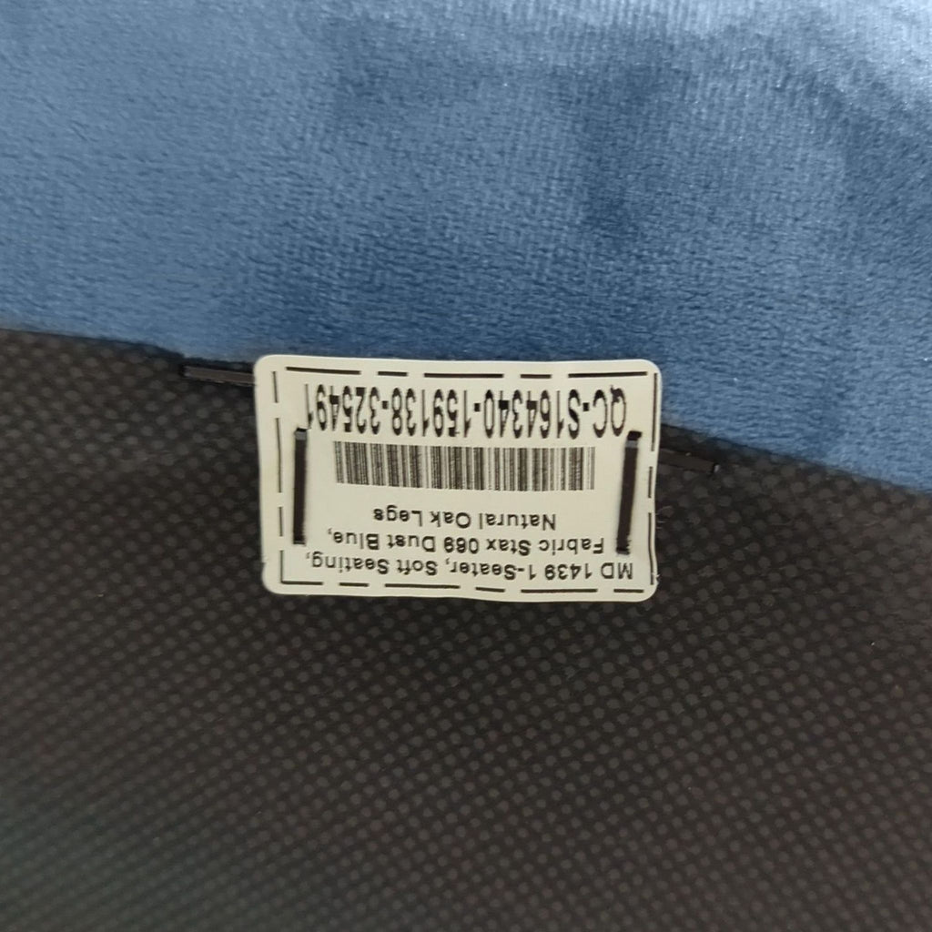Close-up of the product label on the underside of a dust blue velvet Industry West lounge chair.