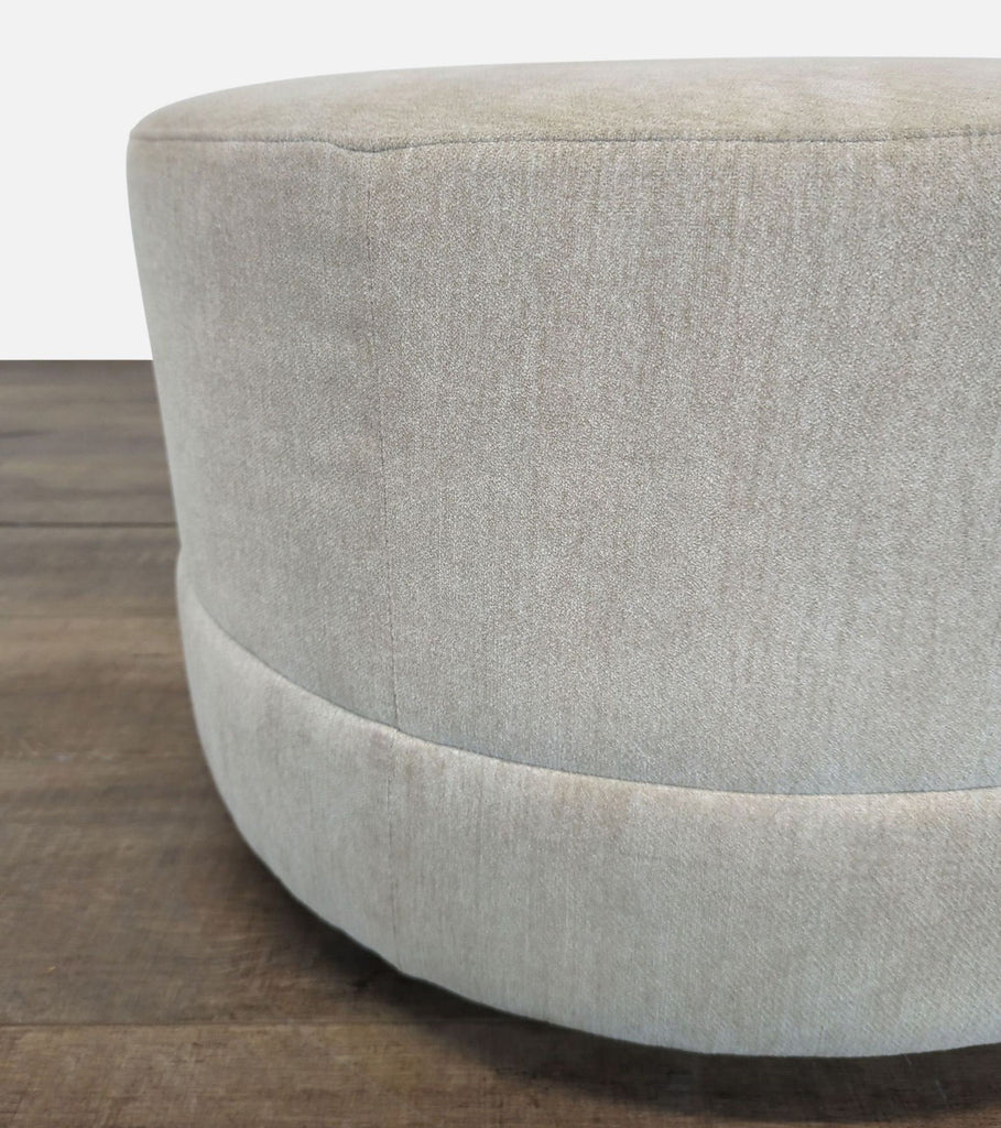 3. Side detail of a Reperch ottoman highlighting plush upholstery and round design on wood flooring.