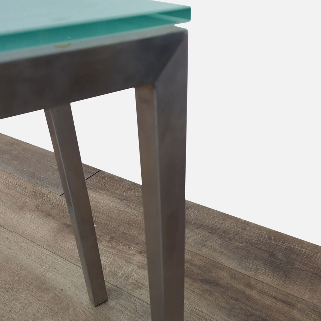 3. Angled view of the Reperch side table’s chrome leg and glass top, emphasizing modern design.