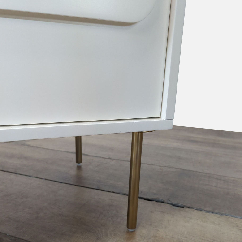 3. Close-up of gold-colored metal legs on a white Williams Sonoma dresser from the Dressers category.