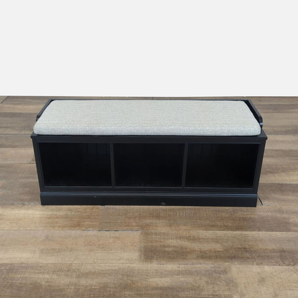 1. Pottery Barn bench with black wood frame, three cubby compartments, and a light upholstered cushion top.