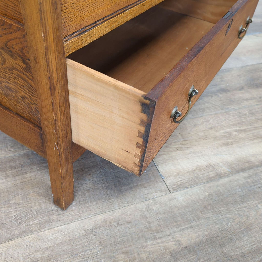 3. Close-up of a dovetail joint and brass pull on an open drawer of an oak Reperch dresser.