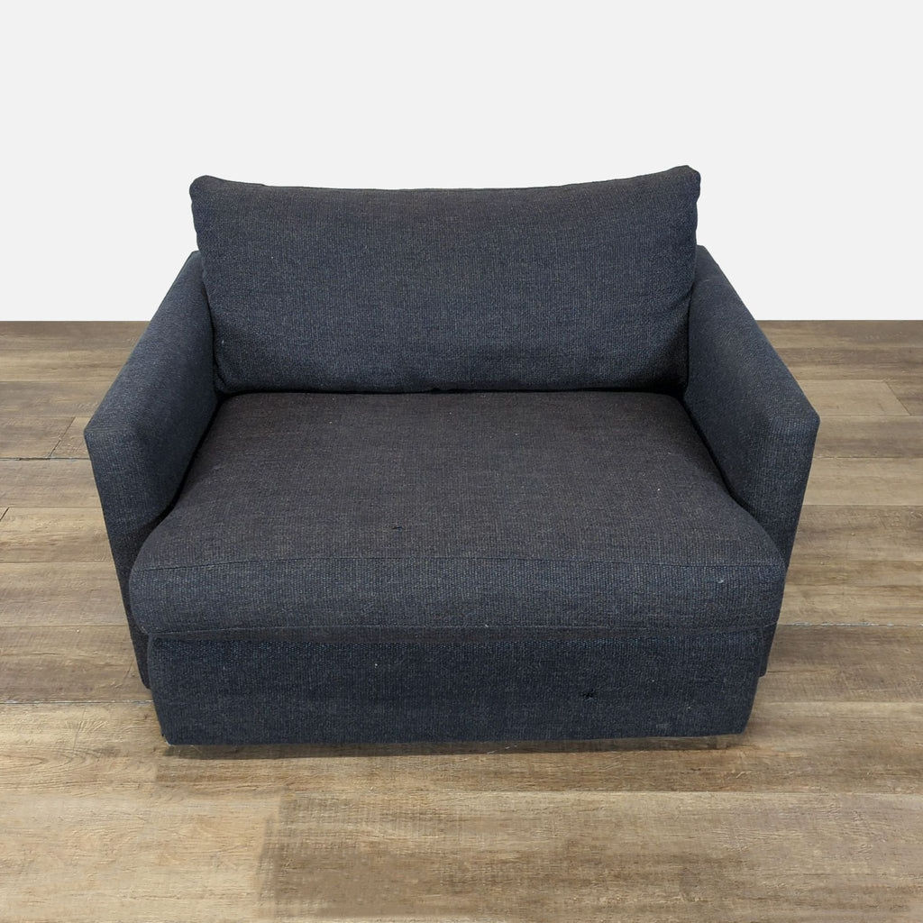 Front view of a dark fabric lounge chair by Crate & Barrel, featuring a deep low seat and slim track arms.