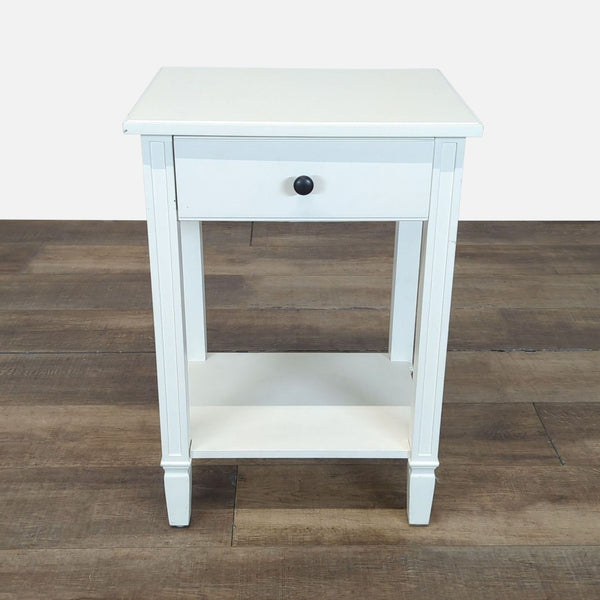 1. White Reperch side table with a drawer and lower shelf, shown on a wooden floor, viewed from the front.