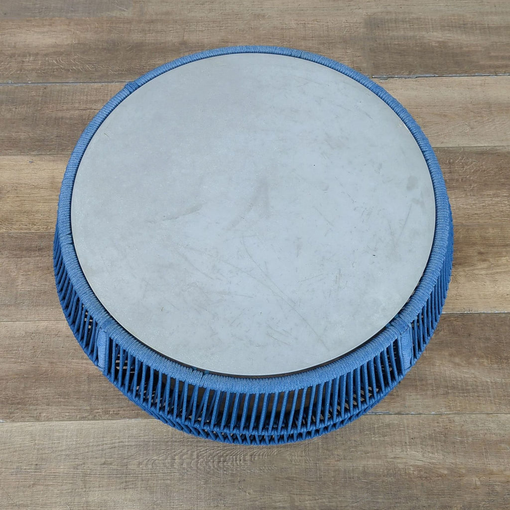 Top view of a Reperch table, featuring a circular stone top and wide blue woven rope base.  