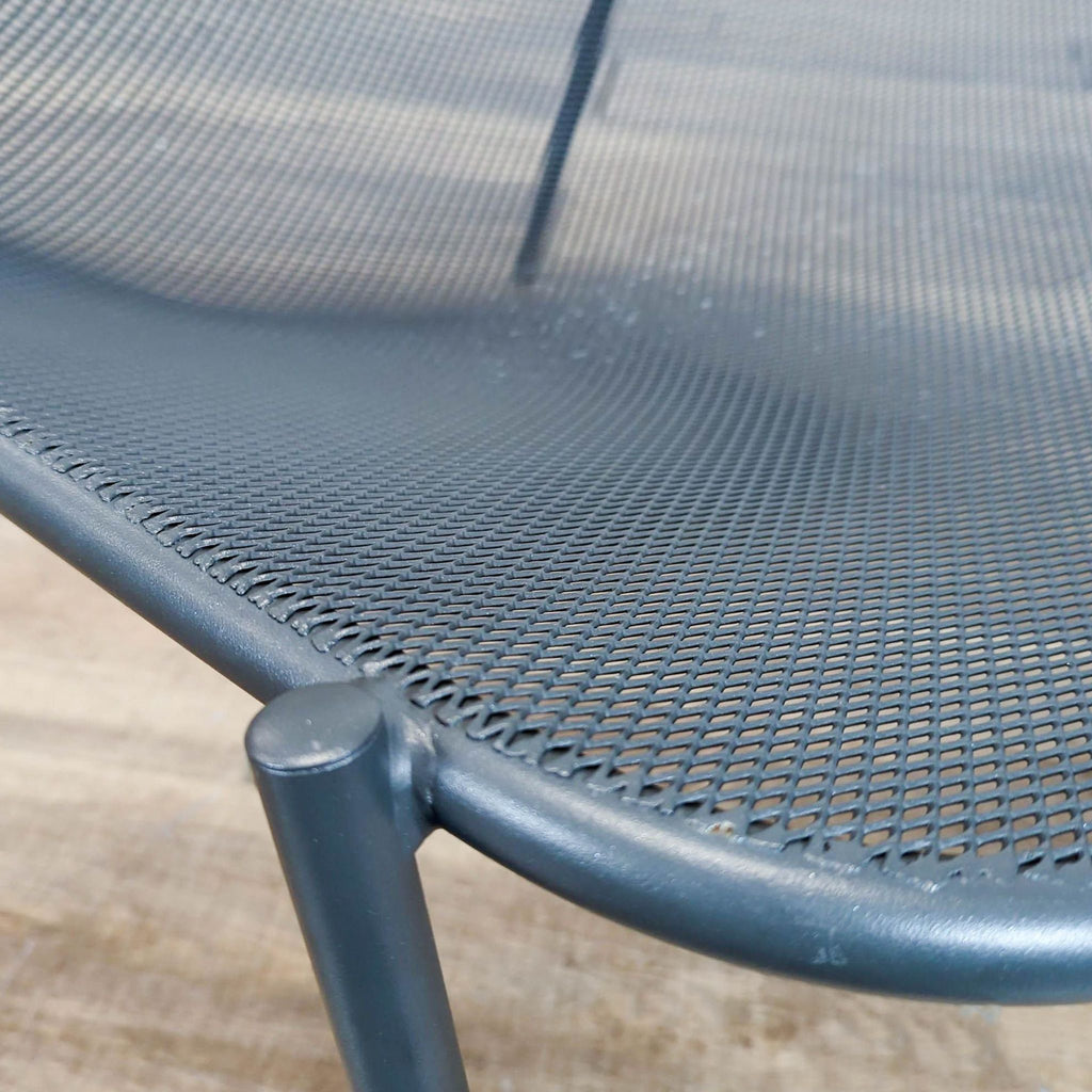 - Close-up of the Reperch chair's metal mesh seat and steel tube frame, highlighting its textured details.