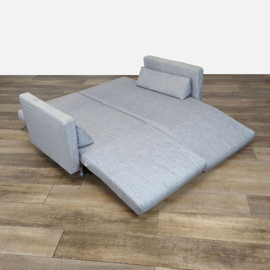 2. Bo Concept loveseat fully folded out into a full-size sleeper sofa on a wooden floor.