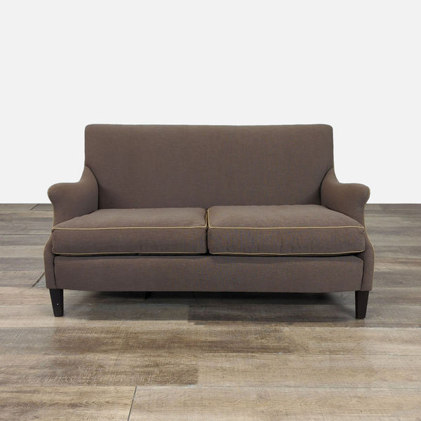 1. Brown Cisco Brothers loveseat with rounded, rolled arms and dark wood legs, front view on wood floor.