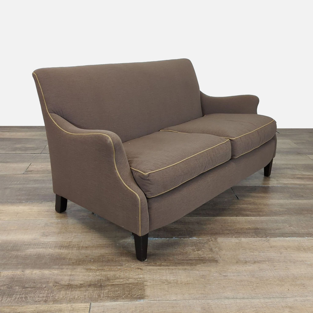 2. Angled view of a brown loveseat with tailored upholstery, rolling arms, and dark-finish legs by Cisco Brothers.