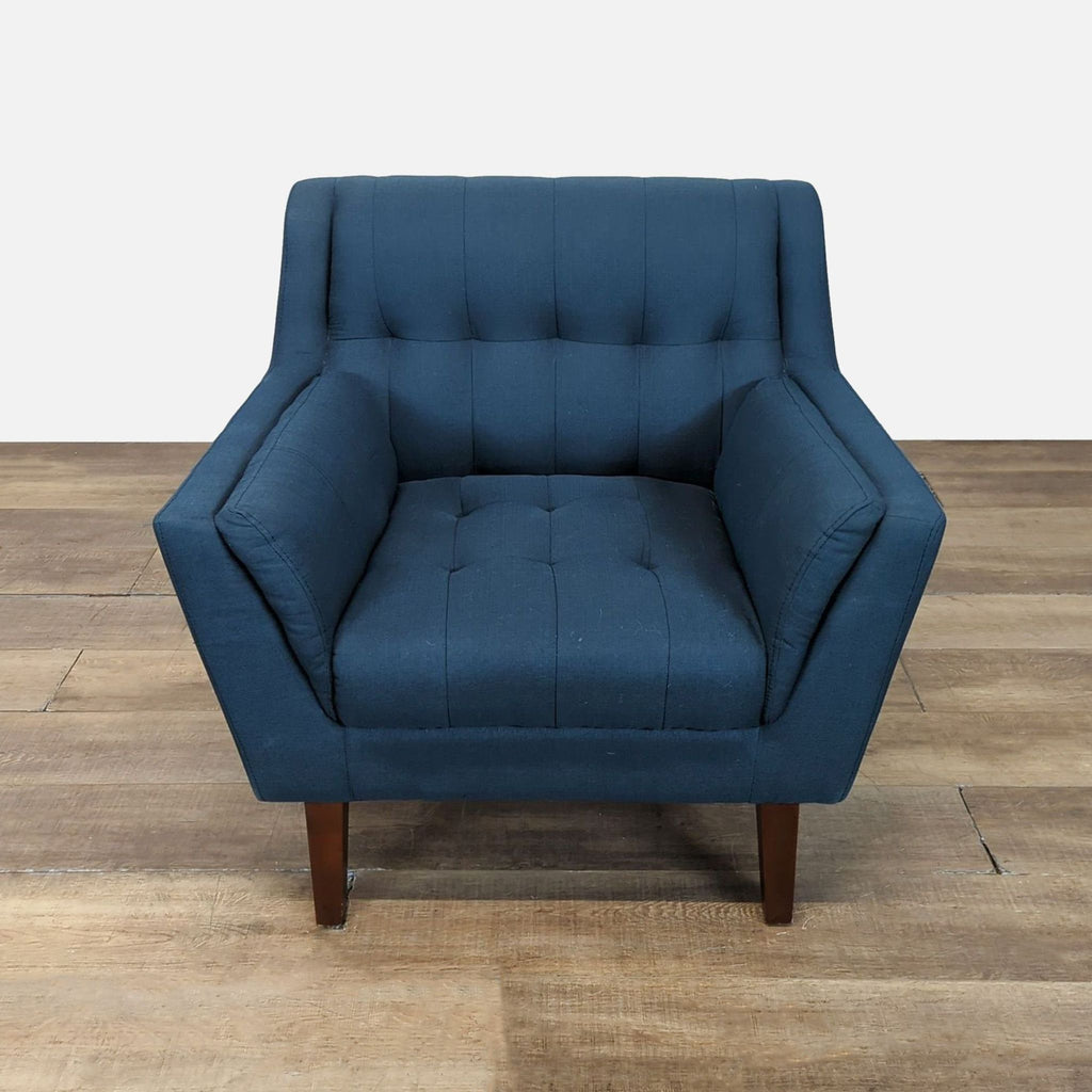 1. Front view of a Reperch lounge chair with blue tufted seat and back, and angular wooden legs.