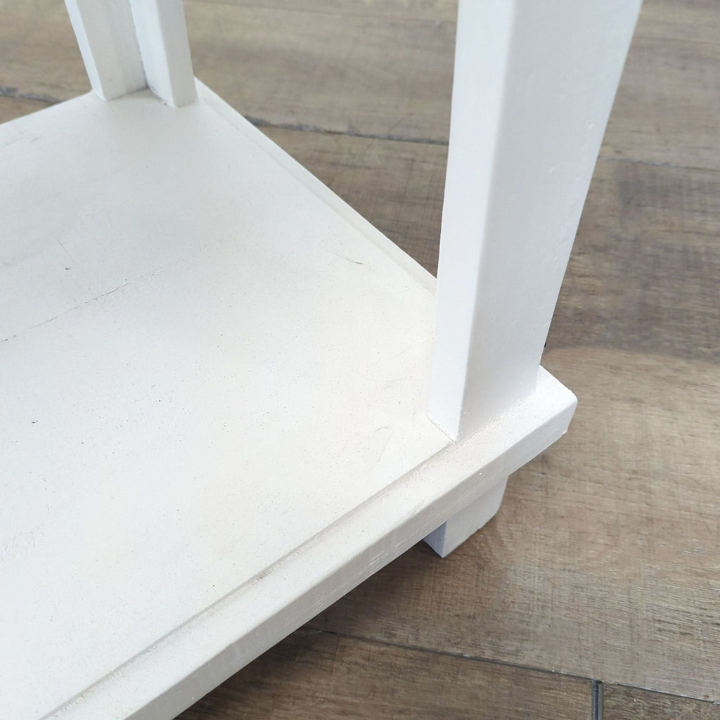 Close-up of the white base and leg of a Rustic Furniture Depot side and console table, highlighting details.