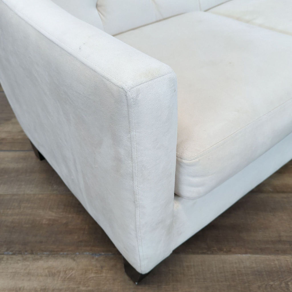1. Close-up of a light-colored upholstered armrest and seat from Ashley Furniture, shown on a wood floor.
