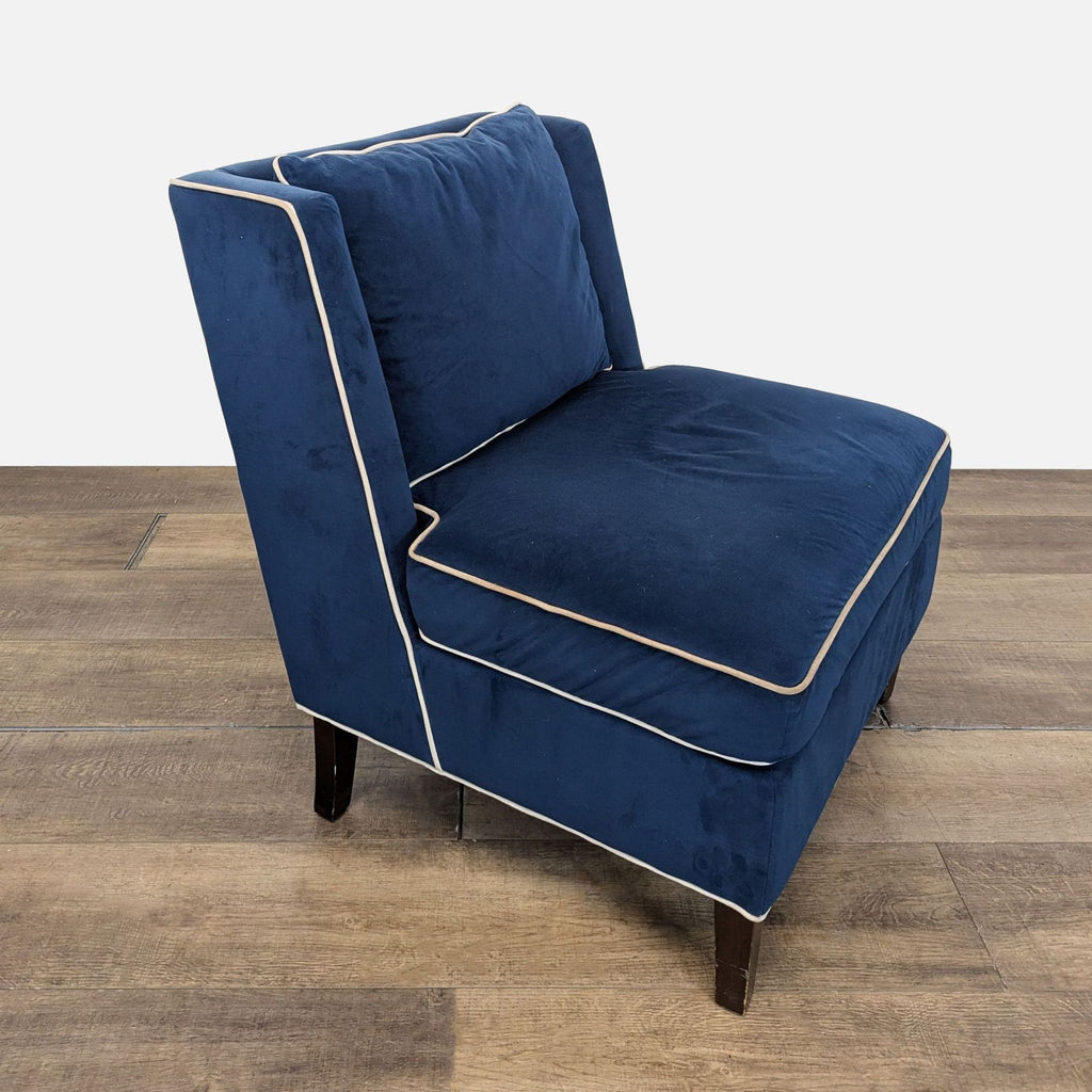 2. Angled side view of a Reperch navy blue velvet lounge chair, showing white piping and dark legs.  