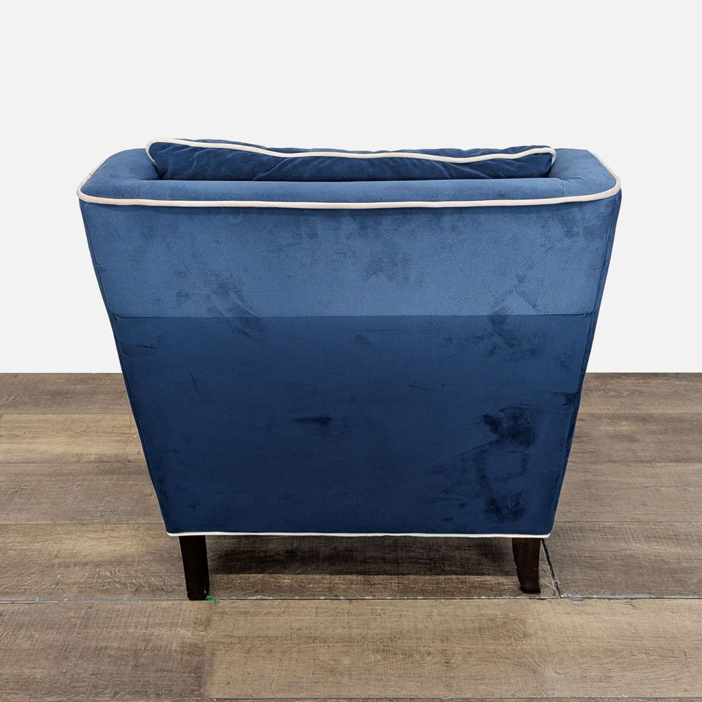 3. Rear view of a Reperch lounge chair featuring navy blue velvet fabric with white piping trim.