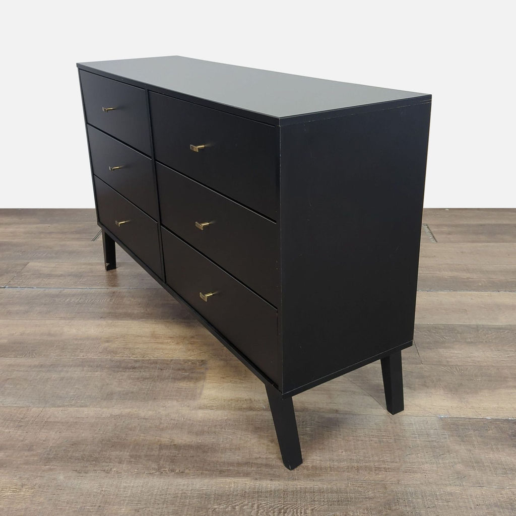2. Angled side view of Prepac black 6-drawer dresser, featuring brass knobs and tapered legs on wood floor.  