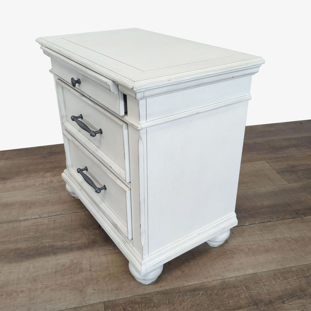 Ashley Furniture end table in distressed white, featuring metal handles and classic design, angled side view.  
