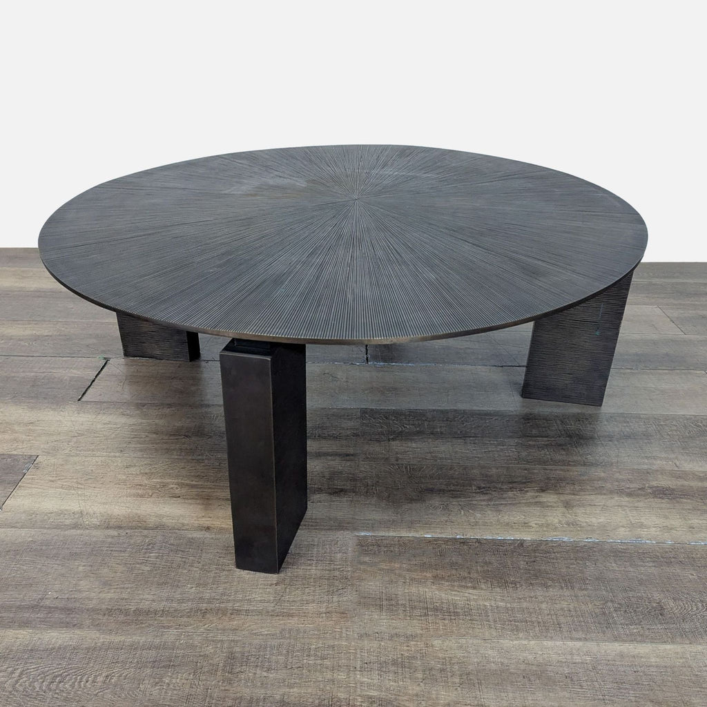 1. Round dark Reperch coffee table with textured radial top and sturdy angled legs, set on wood flooring.