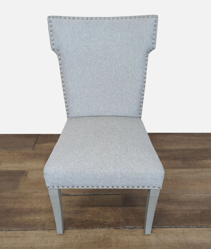 1. Front view of a Reperch dining chair with light grey upholstery and nailhead trim on wooden floor.