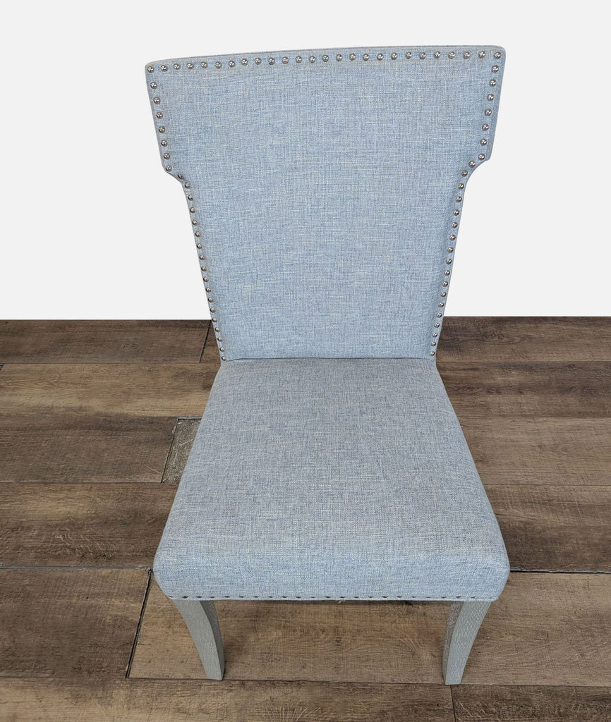 2. Overhead view of a Reperch dining chair featuring blue fabric and silver nailhead details, sitting on wood.