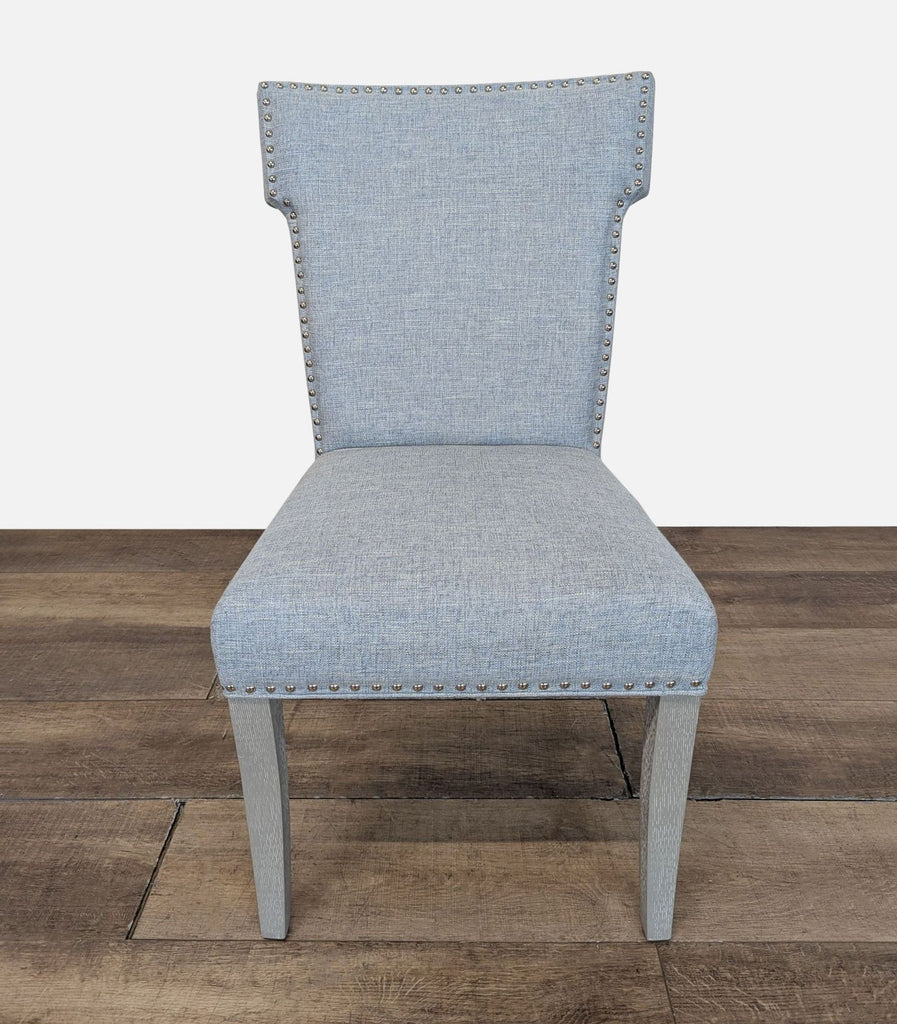 1. Front view of a Reperch dining chair with light blue upholstery and nailhead trim on a wood floor.