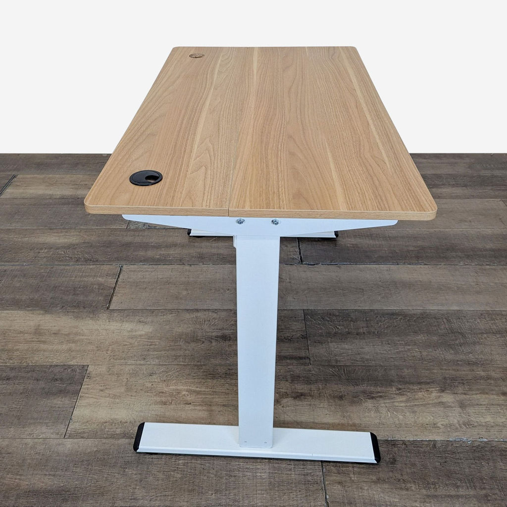 2. Side view of a spacious sit-stand desk with light wood surface, white frame, and dual cable grommets.  