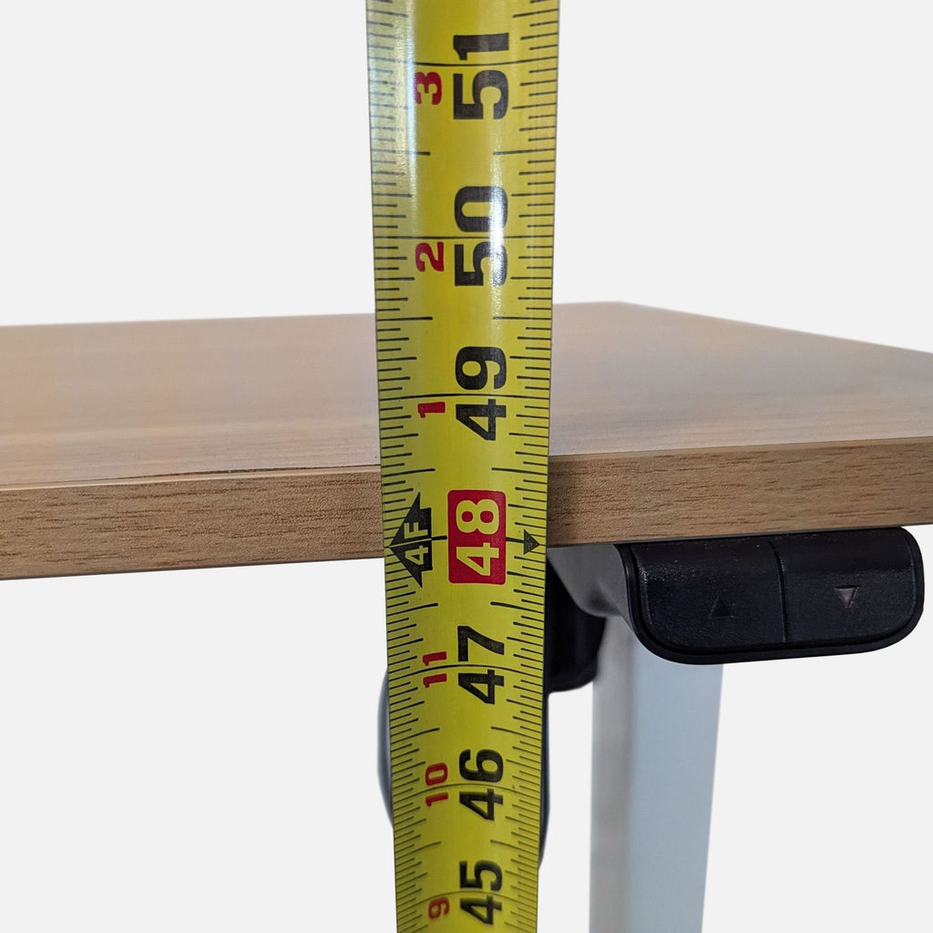 3. Close-up of desk's height being measured with tape, showing electronic adjustment buttons under tabletop.