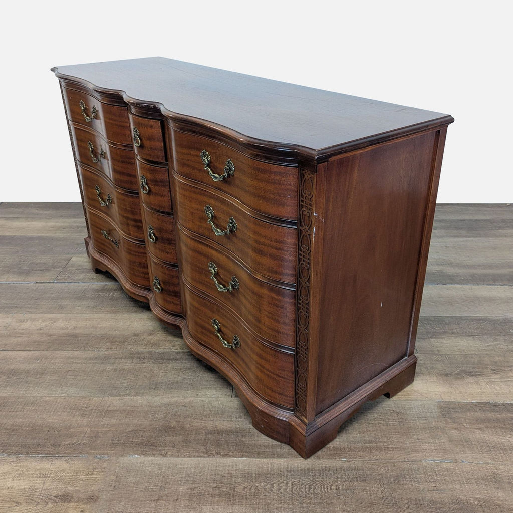 2. Side angle view of a Reperch serpentine dresser with detailed carved trim and antique brass handles.
